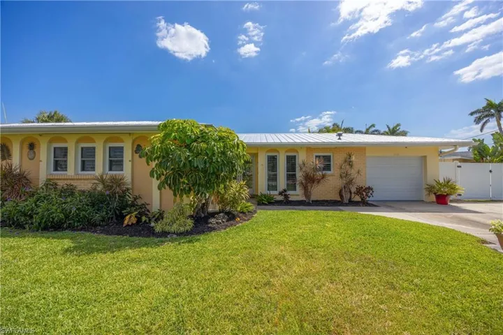 Single story home featuring a garage, a front yard, stucco siding, brick siding, and driveway