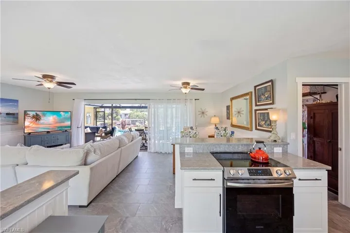 Kitchen with electric stove, white cabinetry, a ceiling fan, and open floor plan
