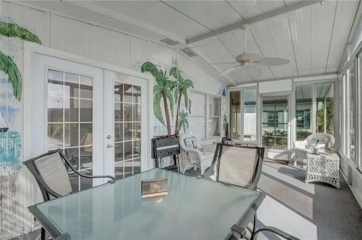 Sunroom / solarium featuring french doors, outdoor dining area, ceiling fan, and beam ceiling