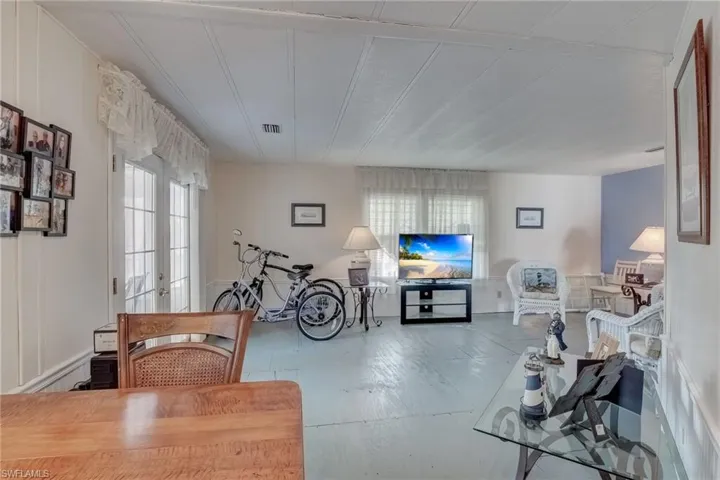Living room featuring plenty of natural light, a decorative wall, and french doors