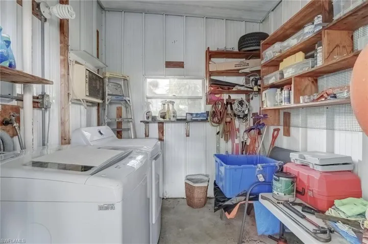 Laundry area with unfinished concrete floors, metal wall, and washing machine and clothes dryer