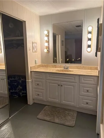 Bathroom vanity featuring a light-toned countertop, white cabinetry with silver-toned hardware, and a large wall-mounted mirror