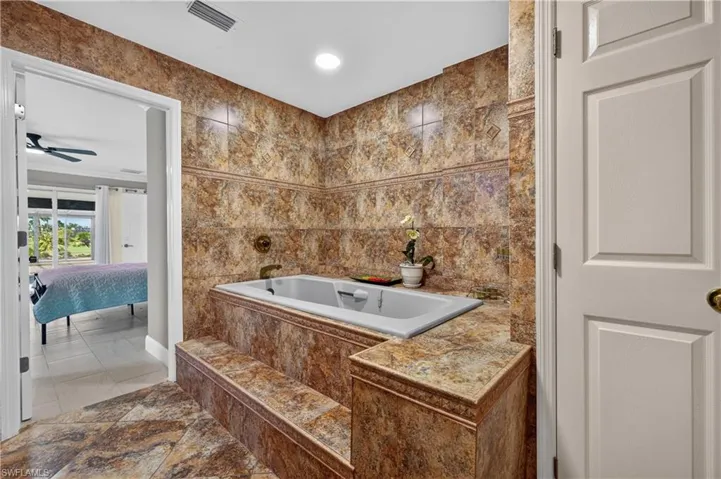 Tiled soaking tub featuring integrated steps and coordinated wall and floor tiling