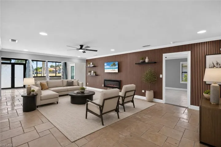 Spacious living area featuring large format tile flooring, a slatted accent wall, recessed lighting, and an electric fireplace, Virtually Staged