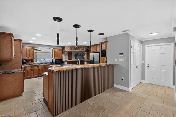 Kitchen featuring wood cabinetry, a central island with a slatted base, and a breakfast bar