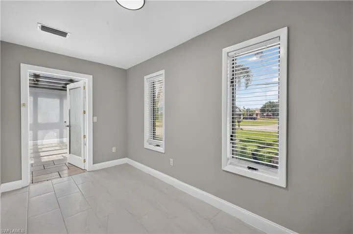 Room featuring light gray walls, white baseboards, and light-toned tile flooring