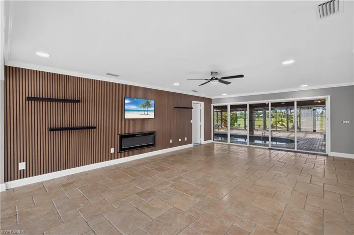 Spacious room featuring a slat accent wall with an inset electric fireplace, recessed lighting, and a ceiling fan