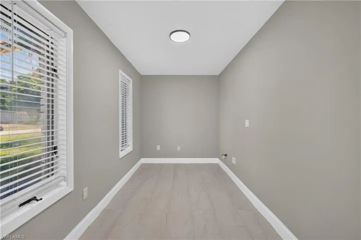 Rectangular interior space featuring light gray wall paint and contemporary wood-finish plank flooring