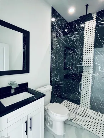 Bathroom featuring vanity and a marble finish shower