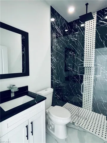 Full bath featuring vanity and a marble finish shower
