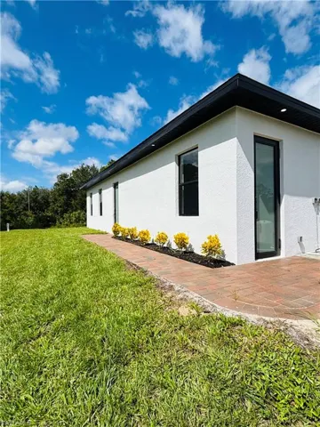 View of side of home featuring a lawn and stucco siding