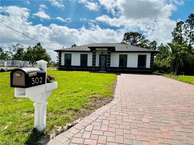 Prairie-style house featuring a front lawn, stucco siding, and decorative driveway