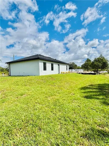 Rear view of property featuring a yard and stucco siding