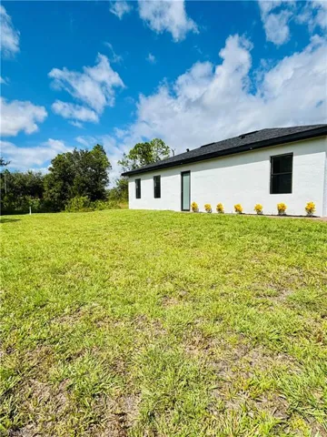 Back of house featuring a lawn and stucco siding