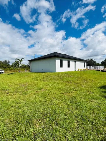 View of side of property featuring stucco siding and a lawn