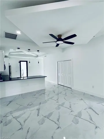 Unfurnished living room with light marble finish floors and a ceiling fan