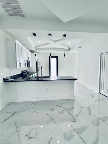 Kitchen featuring decorative light fixtures, white cabinetry, coffered ceiling, range with electric cooktop, and a peninsula
