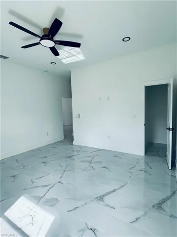 Empty room with light marble finish flooring and a ceiling fan