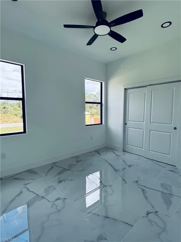 Unfurnished bedroom with marble finish floors, a ceiling fan, a closet, and recessed lighting