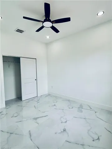 Bedroom featuring light marble finish flooring, a ceiling fan, recessed lighting, and a closet