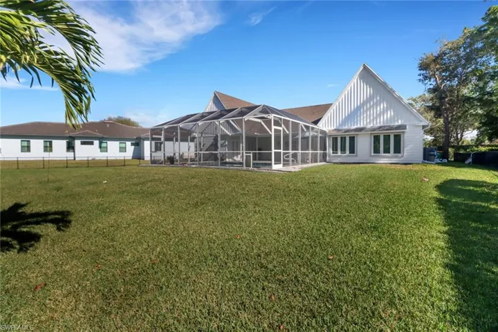 Back of house featuring a lanai and a lawn