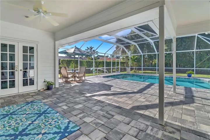 View of swimming pool featuring french doors, a patio, glass enclosure, and ceiling fan