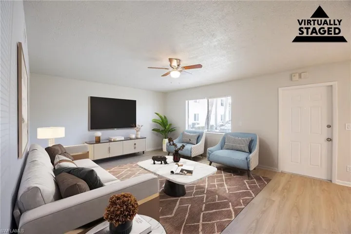 Living area with a textured ceiling, ceiling fan, and wood finished floors