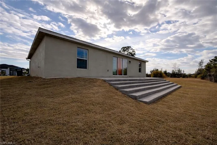 Rear view of house with a yard, stucco siding, and a patio