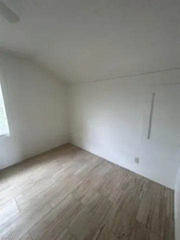 Unfurnished room featuring vaulted ceiling and wood finished floors