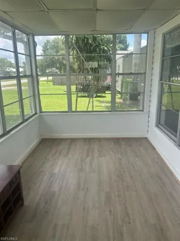 Unfurnished sunroom with wood finished floors and a drop ceiling