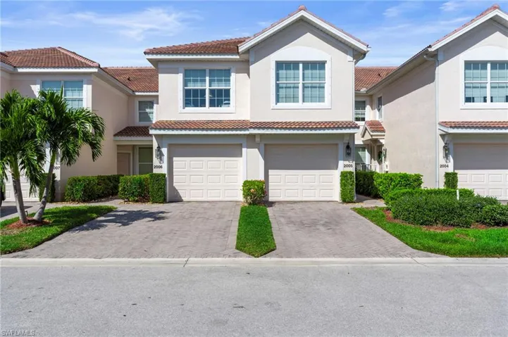 First Floor Carriage Style Home featuring decorative driveway, an attached garage, a tile roof, and stucco siding