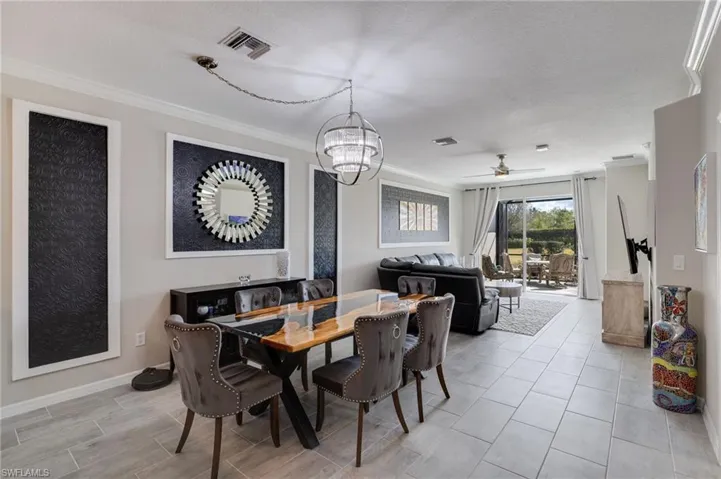Dining space featuring a ceiling fan, ornamental molding, a chandelier, and a textured ceiling