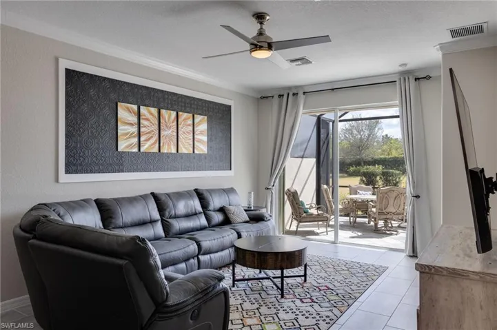 Living room featuring a ceiling fan, ornamental molding, a textured ceiling, and light tile patterned floors