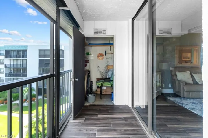 Laundry area with stacked washer and clothes dryer and dark wood finished floors