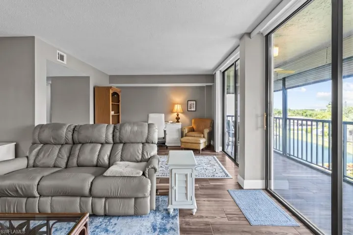 Living area with dark wood-style flooring, a textured ceiling, and recessed lighting