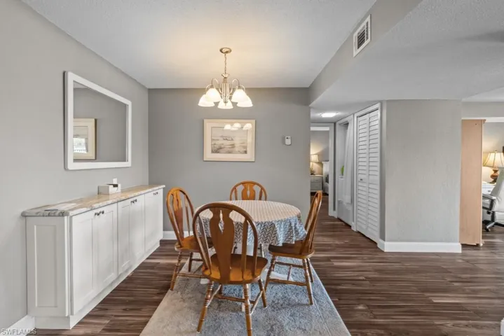 Dining space featuring dark wood-style flooring and a chandelier