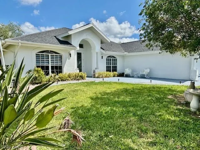 Ranch-style house with a front yard, stucco siding, and roof with shingles