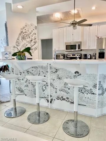 Kitchen featuring white cabinetry, recessed lighting, a breakfast bar area, a ceiling fan, and stainless steel appliances