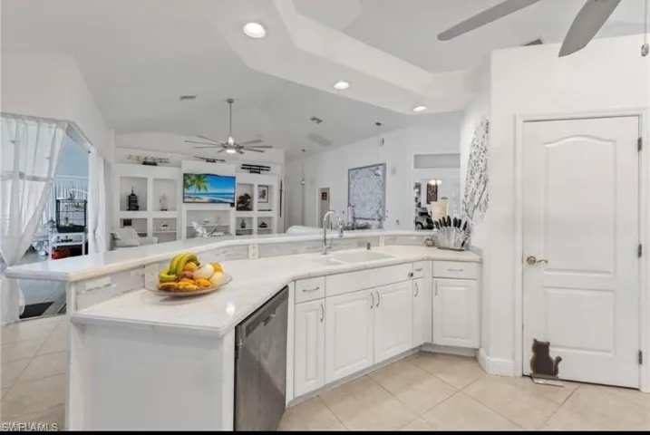 Kitchen with ceiling fan, open floor plan, white cabinetry, dishwasher, and light tile patterned flooring