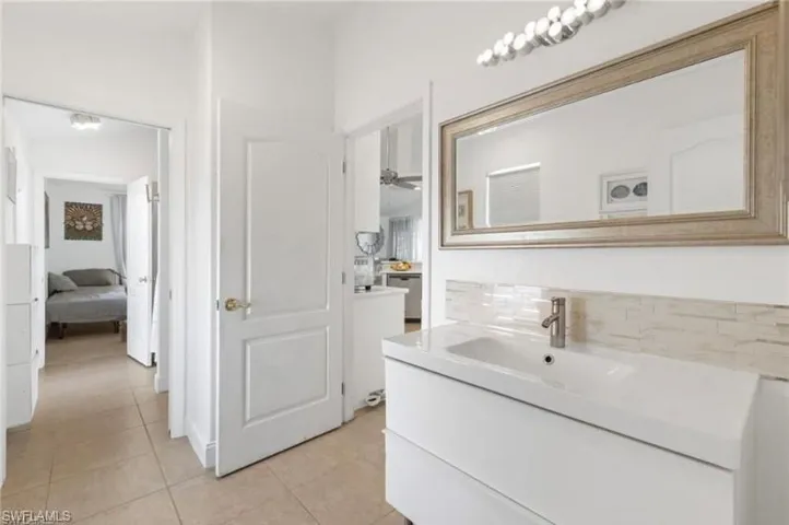 Bathroom in guest suite/ with vanity, decorative backsplash, ensuite bath, and light tile patterned floors