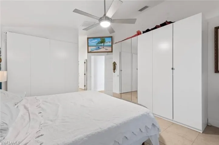 Bedroom featuring a ceiling fan, light tile patterned floors, and two closets