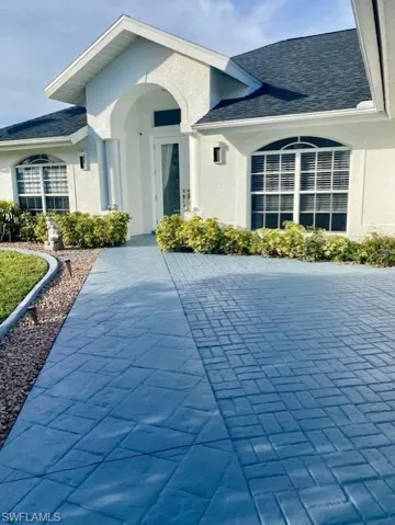 View of exterior entry featuring stucco siding and a shingled roof