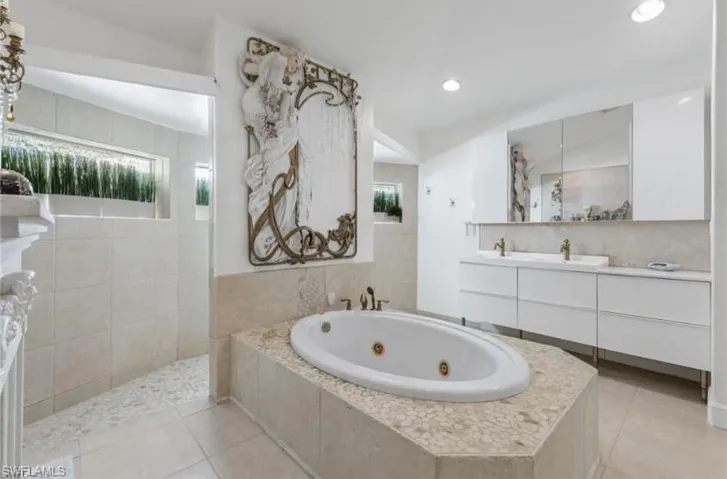 Full bath with vanity, a whirlpool tub, walk through shower, and light tile patterned floors