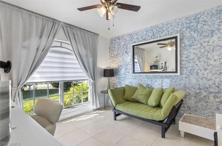 Sitting room in guest suite with a ceiling fan and light tile patterned floors
