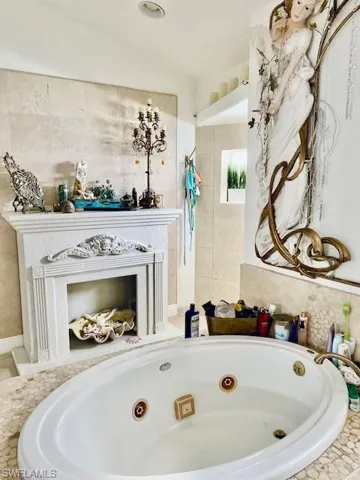 Bathroom featuring a fireplace, a walk in shower, and a tub with jets