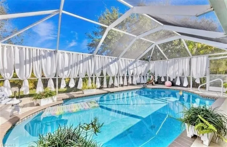 View of swimming pool with a sunroom, a lanai, a fenced backyard, and patio surround