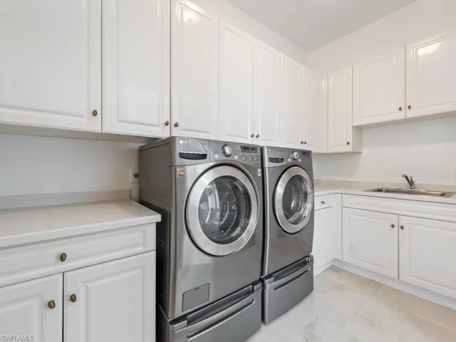 Washroom featuring marble finish floor, a sink, cabinet space, and washer and dryer