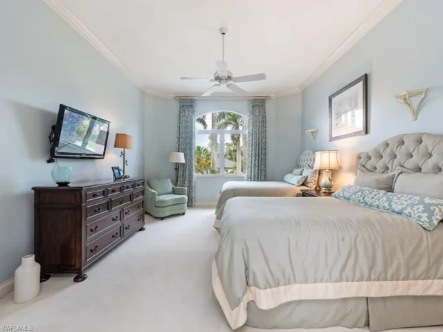 Carpeted bedroom featuring a ceiling fan, ornamental molding, and baseboards