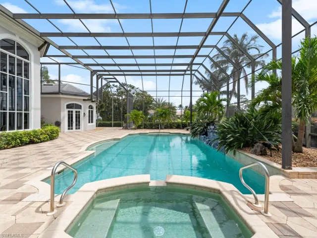 View of swimming pool featuring a pool with connected hot tub, a lanai, a patio, and french doors