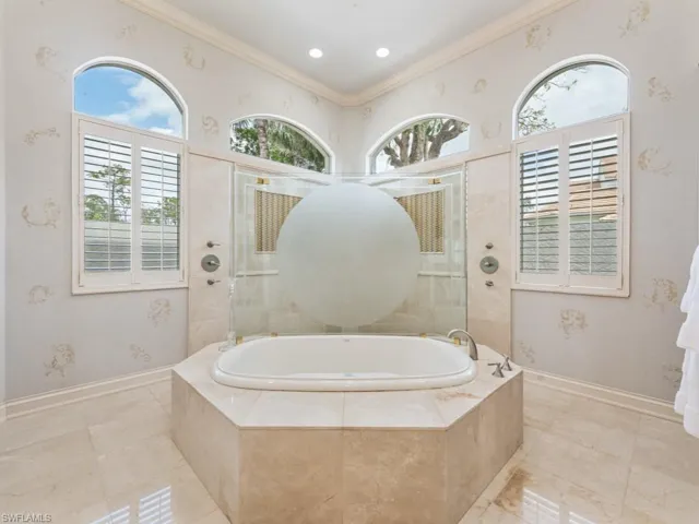 Bathroom featuring tiled shower, ornamental molding, baseboards, and a garden tub